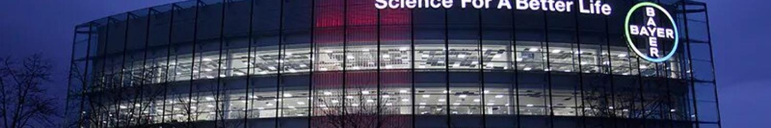 Bayer office building at night with illuminated windows and the slogan "Science For A Better Life" displayed on the facade.